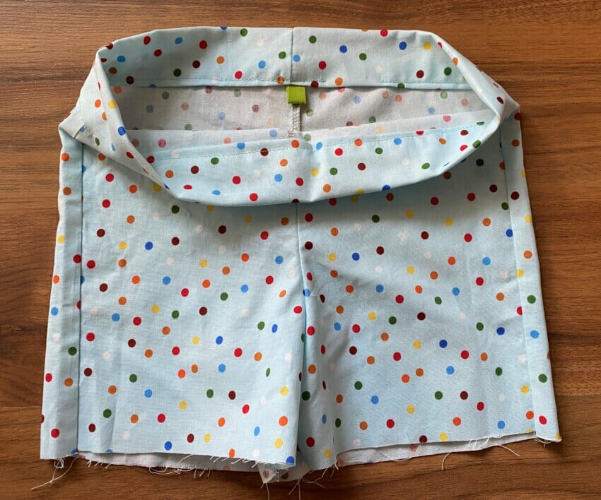 A small, bright loop of contrasting bias tape sewn into the back inner waistband to serve as a handmade size or "back" label