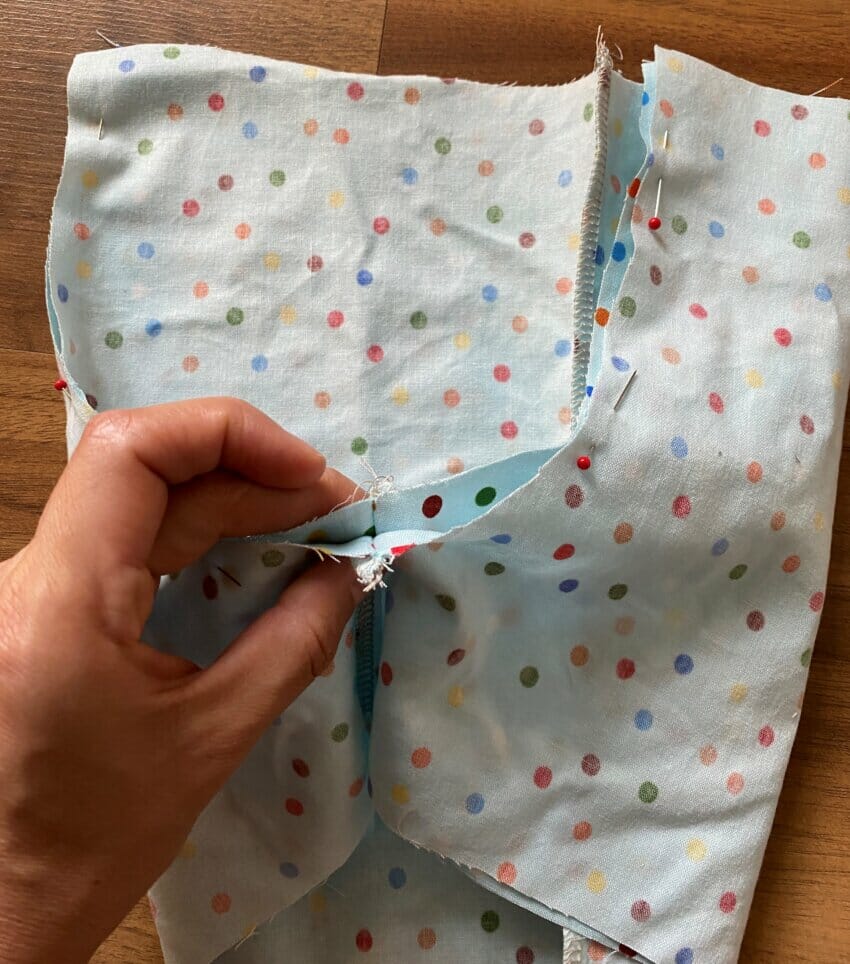 One shorts leg being tucked into the other, right sides together, to align the U-shaped crotch seam before sewing