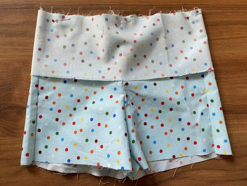 The fabric waistband strip pinned to the top raw edge of the shorts, ready to be sewn into a tube