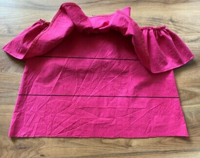 A gathered fabric ruffle pinned along a marked line on the inner connector piece of the skirt
