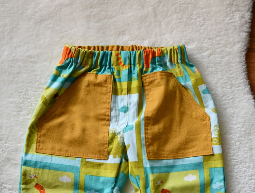 A pair of toddler pants made from dinosaur print cotton fabric featuring a perfectly matched pattern across the front faux fly