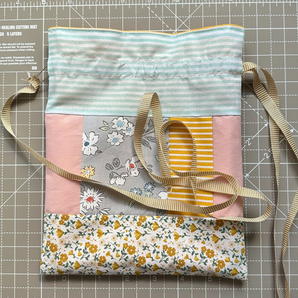 Using a safety pin to feed the drawstring ribbon through the channel of the lined drawstring gift bag
