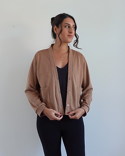 A stylish, size-inclusive Cara cardigan with dropped shoulders, a buttoned front, and cozy ribbed cuffs in a cream-colored knit