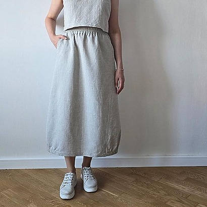 A modern balloon-style midi skirt with princess seams and an elastic drawstring hem that tapers at the bottom