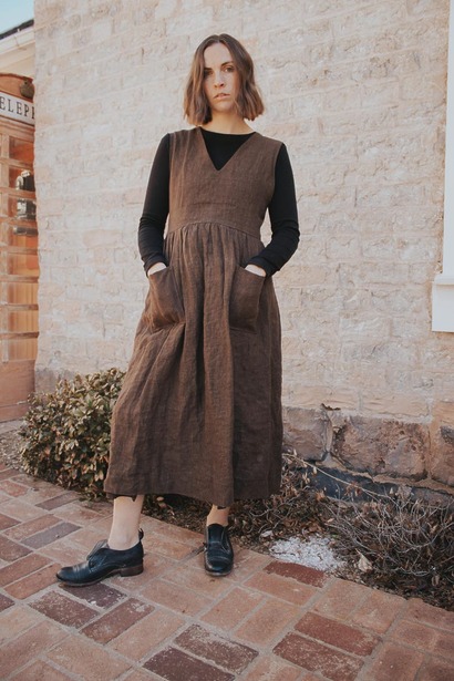 A reversible wrap-style Ginkgo pinafore worn over a black t-shirt, showing a V neckline and a gathered midi-length skirt