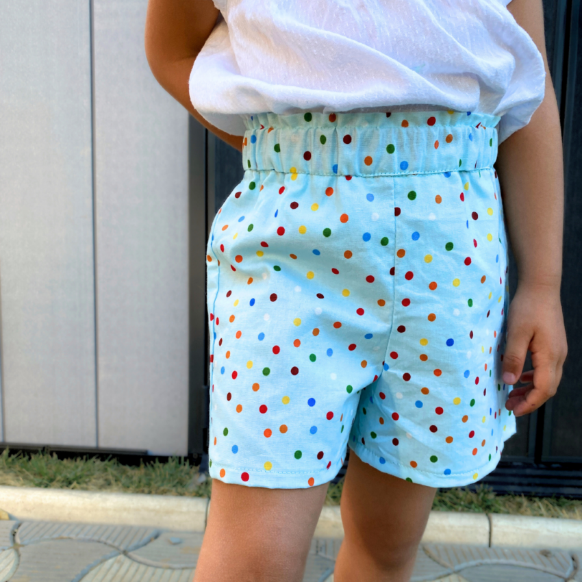 A close-up of the shorts while a child is playing, showing the durable straight-seam construction and the soft drape of the cotton fabric