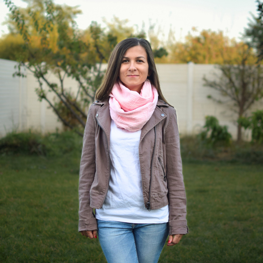 A person wearing a finished, lightweight pink cotton infinity scarf wrapped twice around their neck for a cozy, draped look