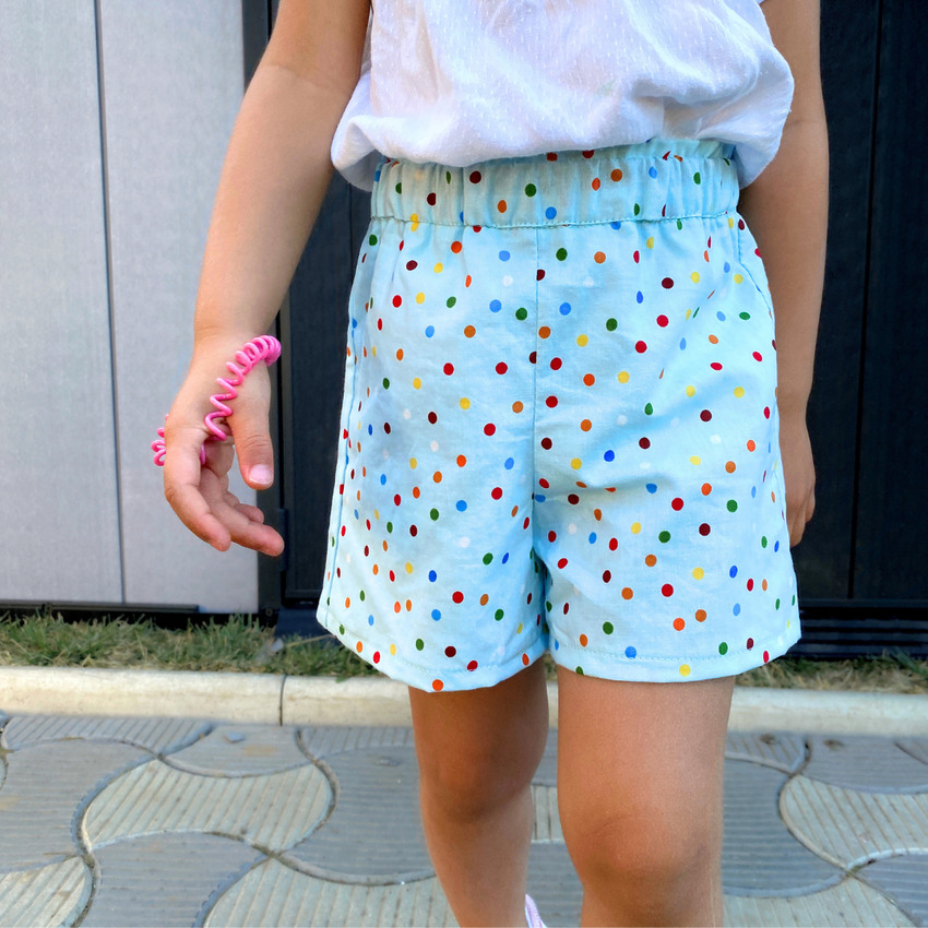 A young girl wearing handmade cotton shorts with a straight hem and a ruffled paper bag waistband