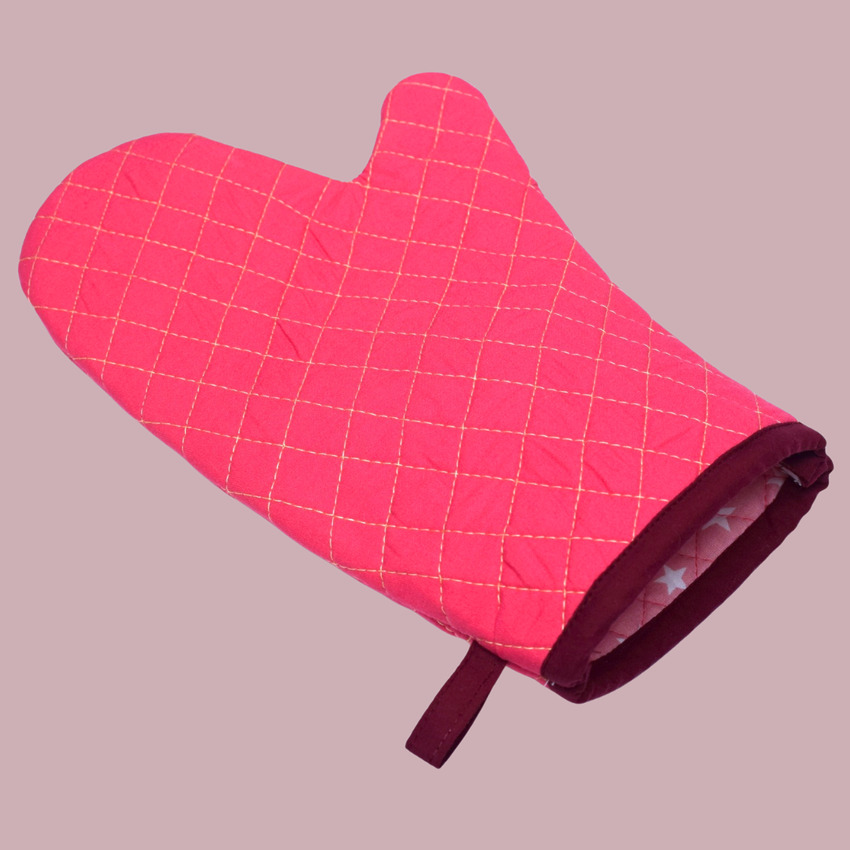 A handmade pink quilted oven mitt with a hanging loop, ready for kitchen use