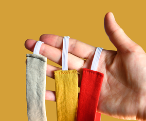 Hand holding three colorful flat cotton headbands with elastic backs made from solid fabrics